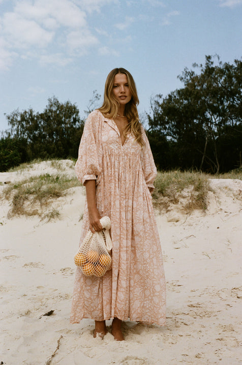Daughters of India Kyra Maxi Dress in Apricot Blush — full length on sand dunes with net bag, hand screen print cotton