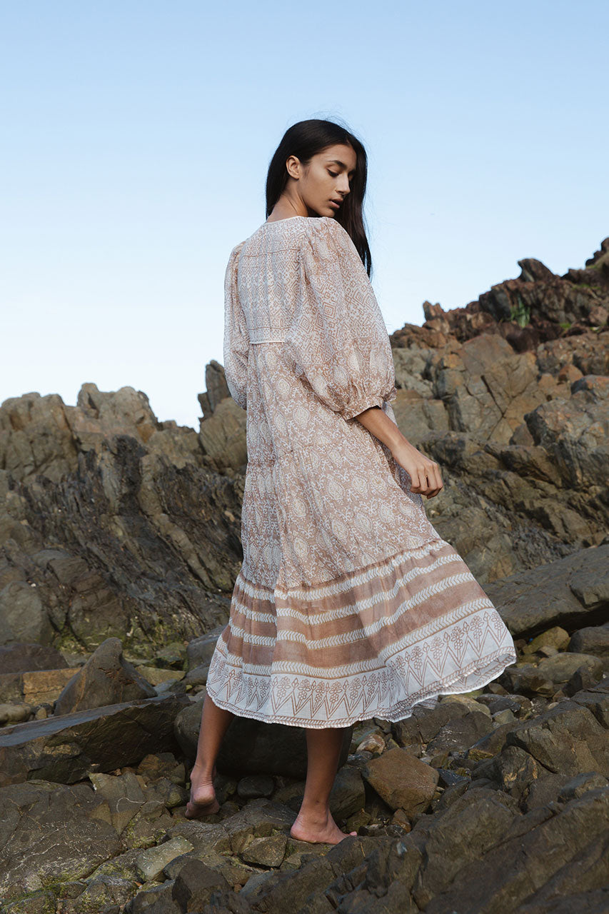 Daughters of India Jasmine Midi Dress in Shell — back view on rocks showing tiered border hem, hand screen print cotton