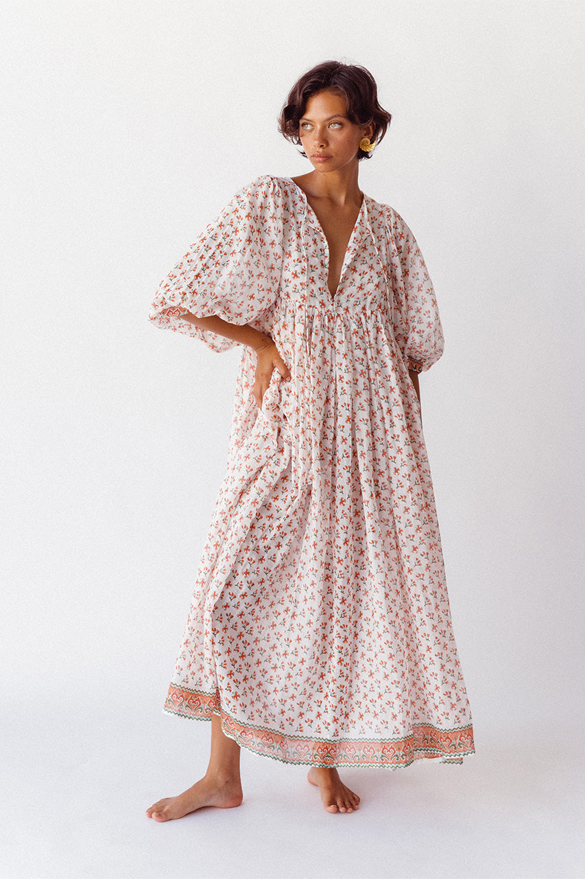 Daughters of India Kyra Maxi Dress in Coral — studio front view hand in pocket, flowing skirt with border hem