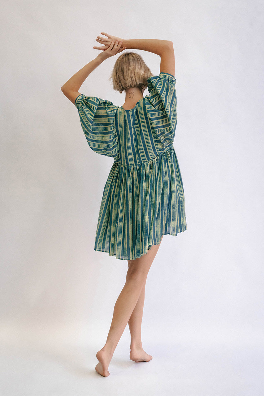 Woman wearing a green and white striped dress against a plain background