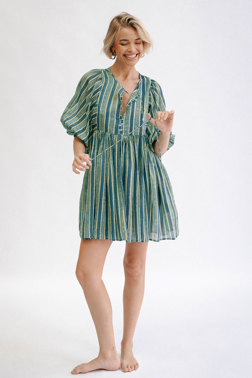 Woman wearing a green and white striped dress on a white background